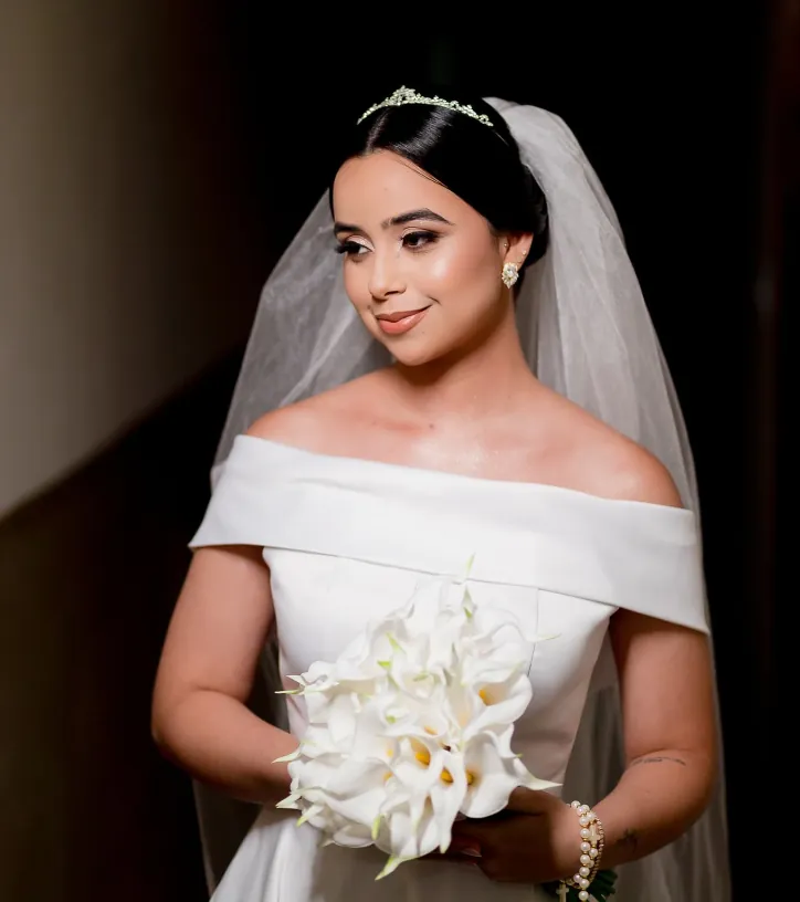 Noiva de vestido ombro a ombro segurando buquê de copos-de-leite