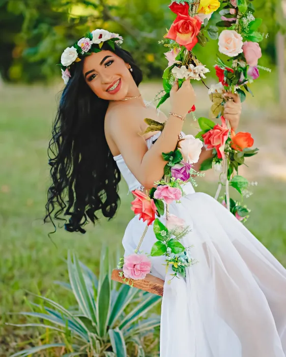 Jovem com coroa de flores sentada em um balanço florido
