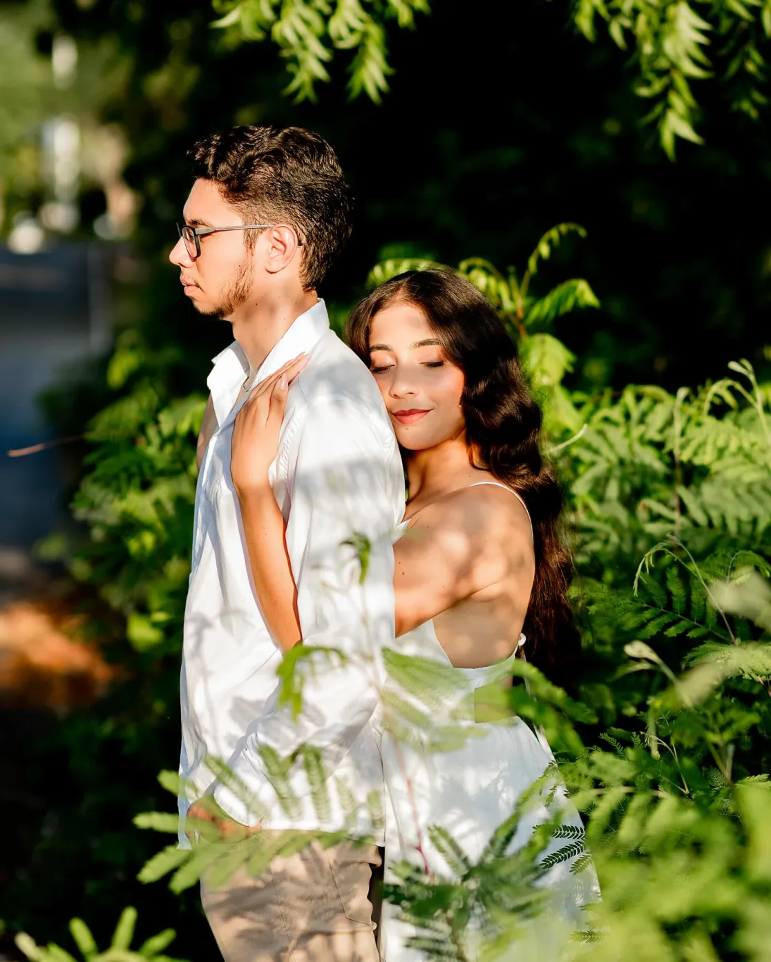 Casal abraçado entre folhagens verdes